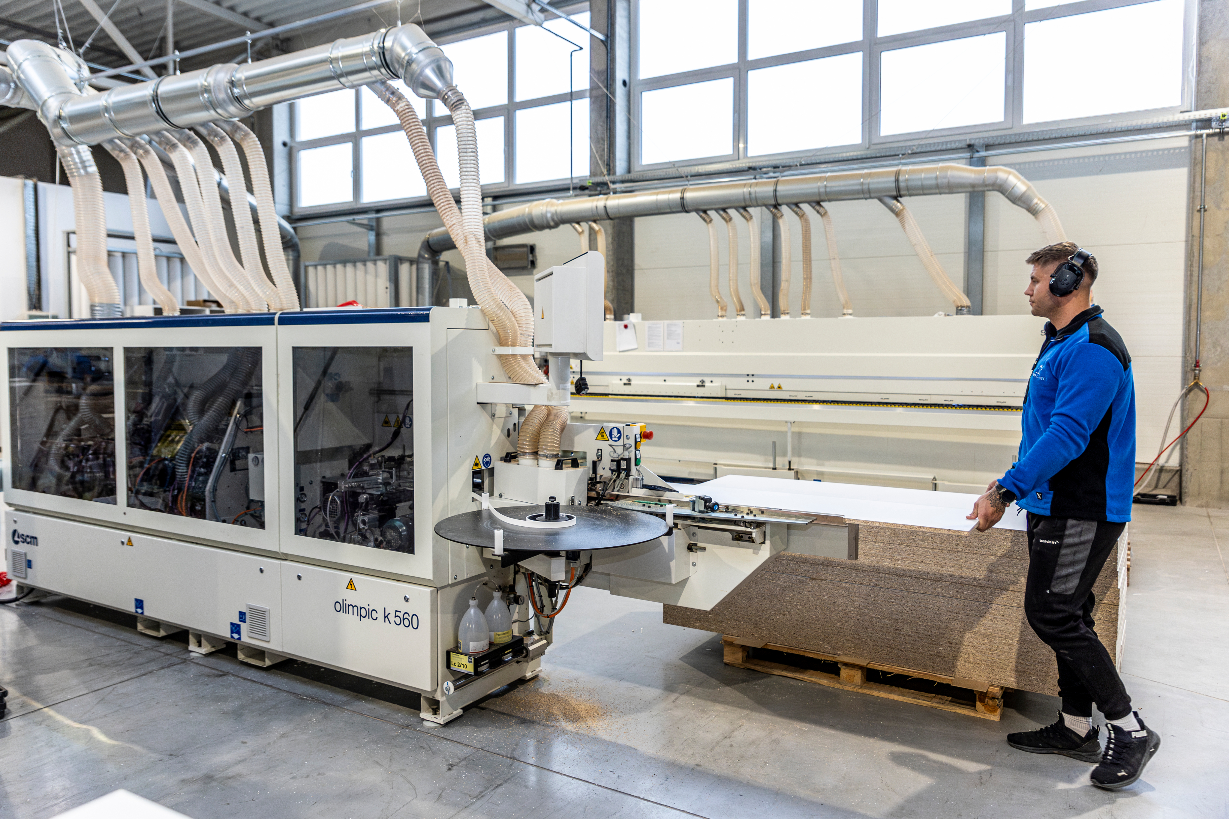 Pracownik przy okleiniarce krawędzi w hali produkcyjnej WoodConnect